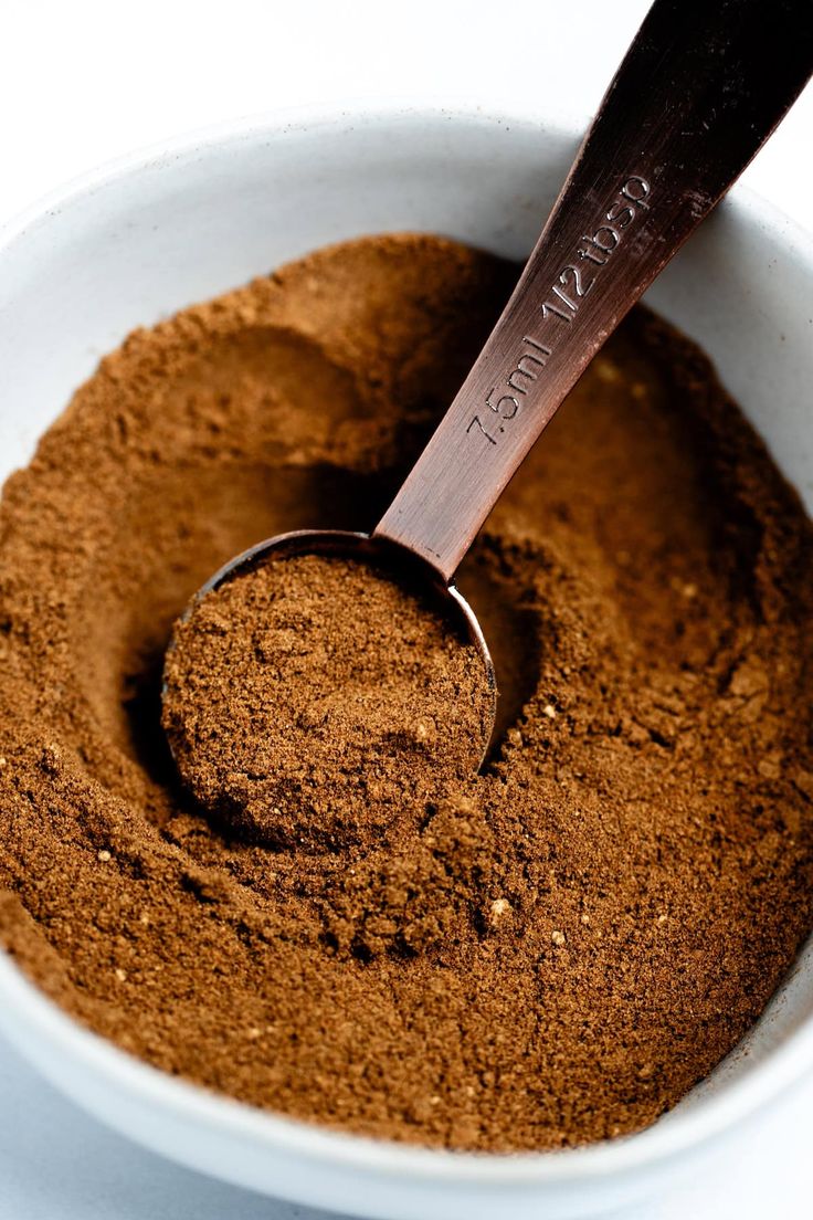 a white bowl filled with brown powder and a wooden spoon