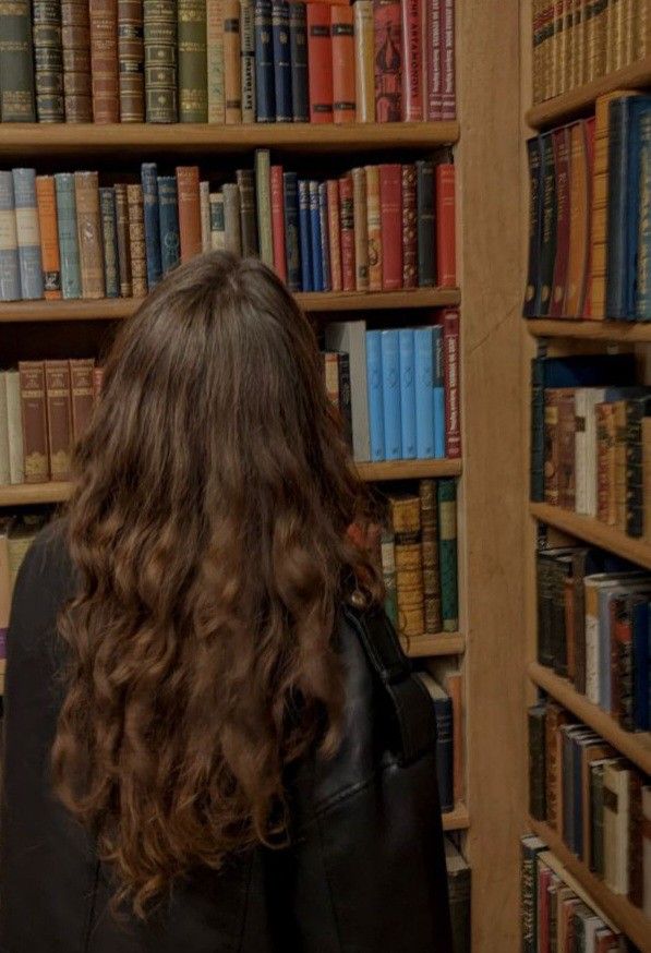 a woman standing in front of a book shelf filled with books