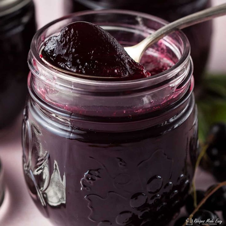 a spoon full of jam sitting on top of a table next to some blackberries