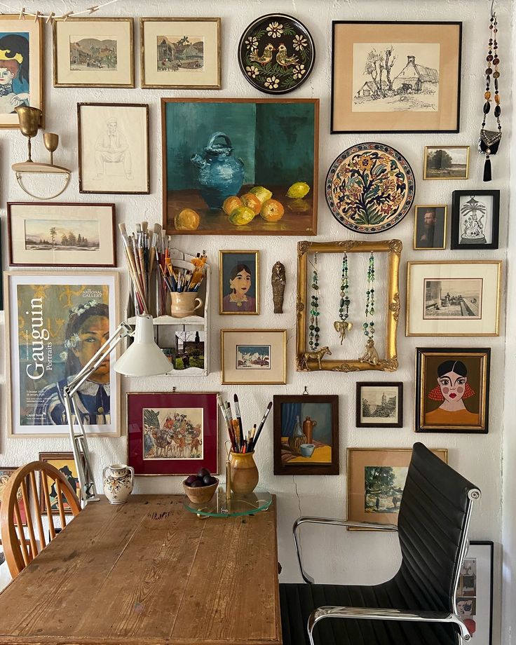 a room filled with lots of framed pictures on the wall next to a wooden table