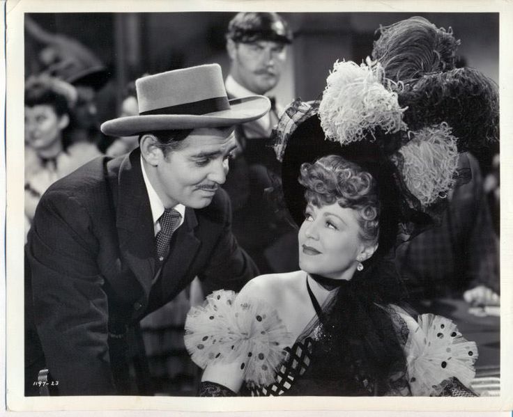 an old black and white photo of a man with a hat talking to a woman