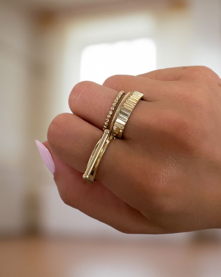 a woman's hand holding a gold ring with two diamonds on the top and bottom