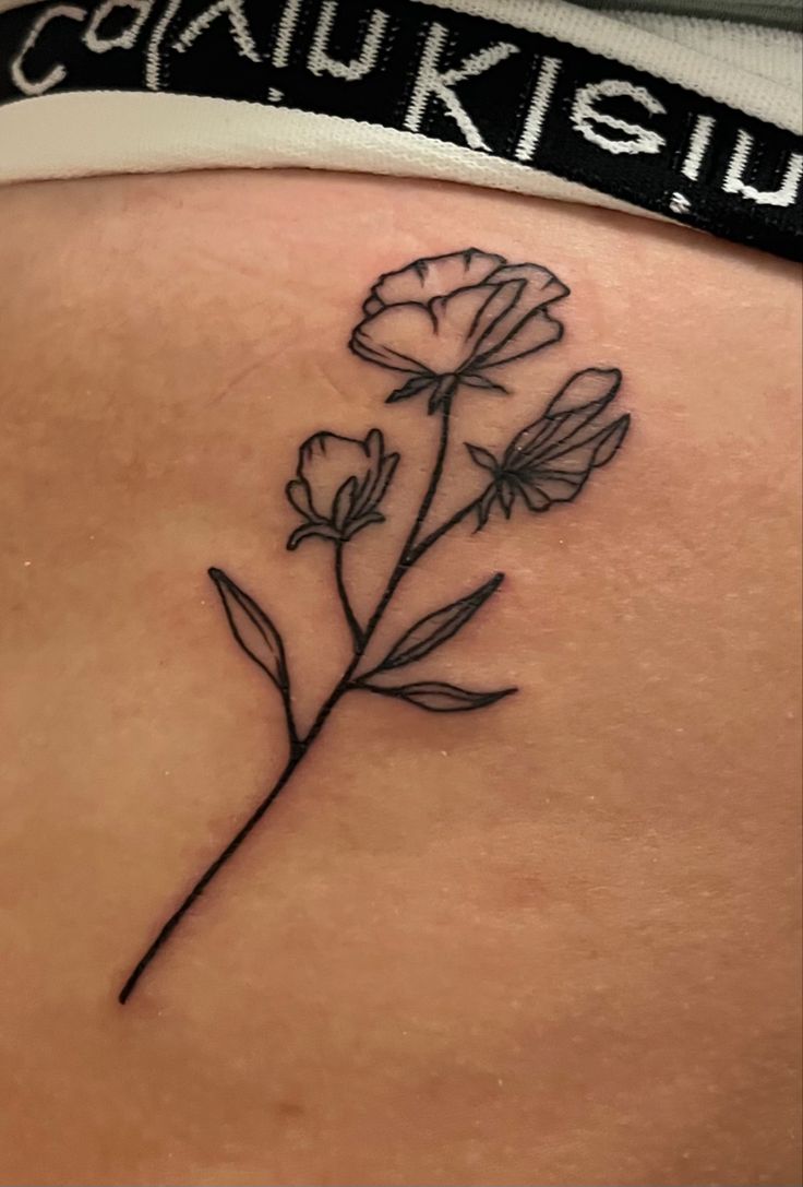 a woman's back with a flower tattoo on her left side ribcage