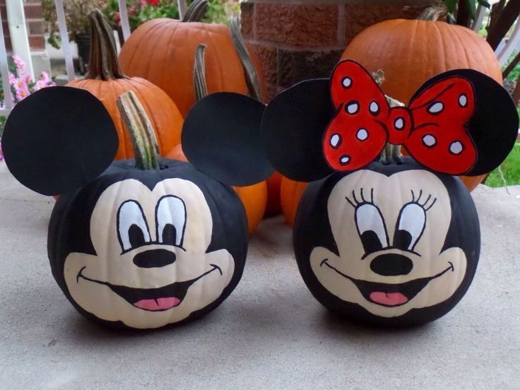 two mickey mouse pumpkins with faces painted on them