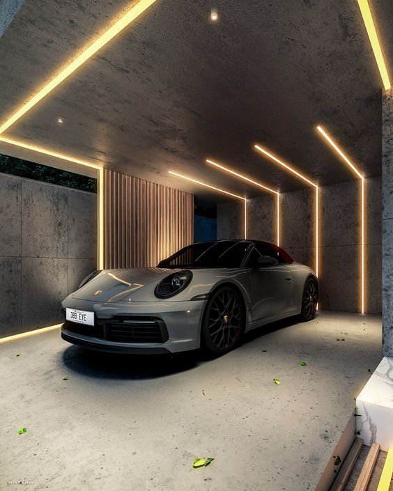 a silver car parked in a garage with lights on the ceiling and concrete flooring