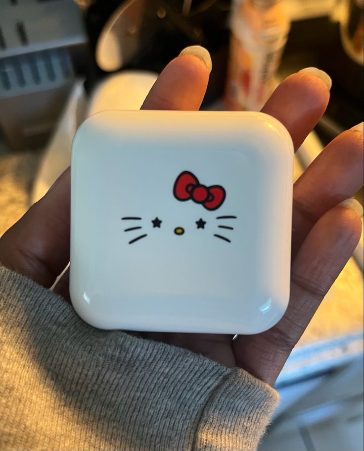 a person is holding a hello kitty square object