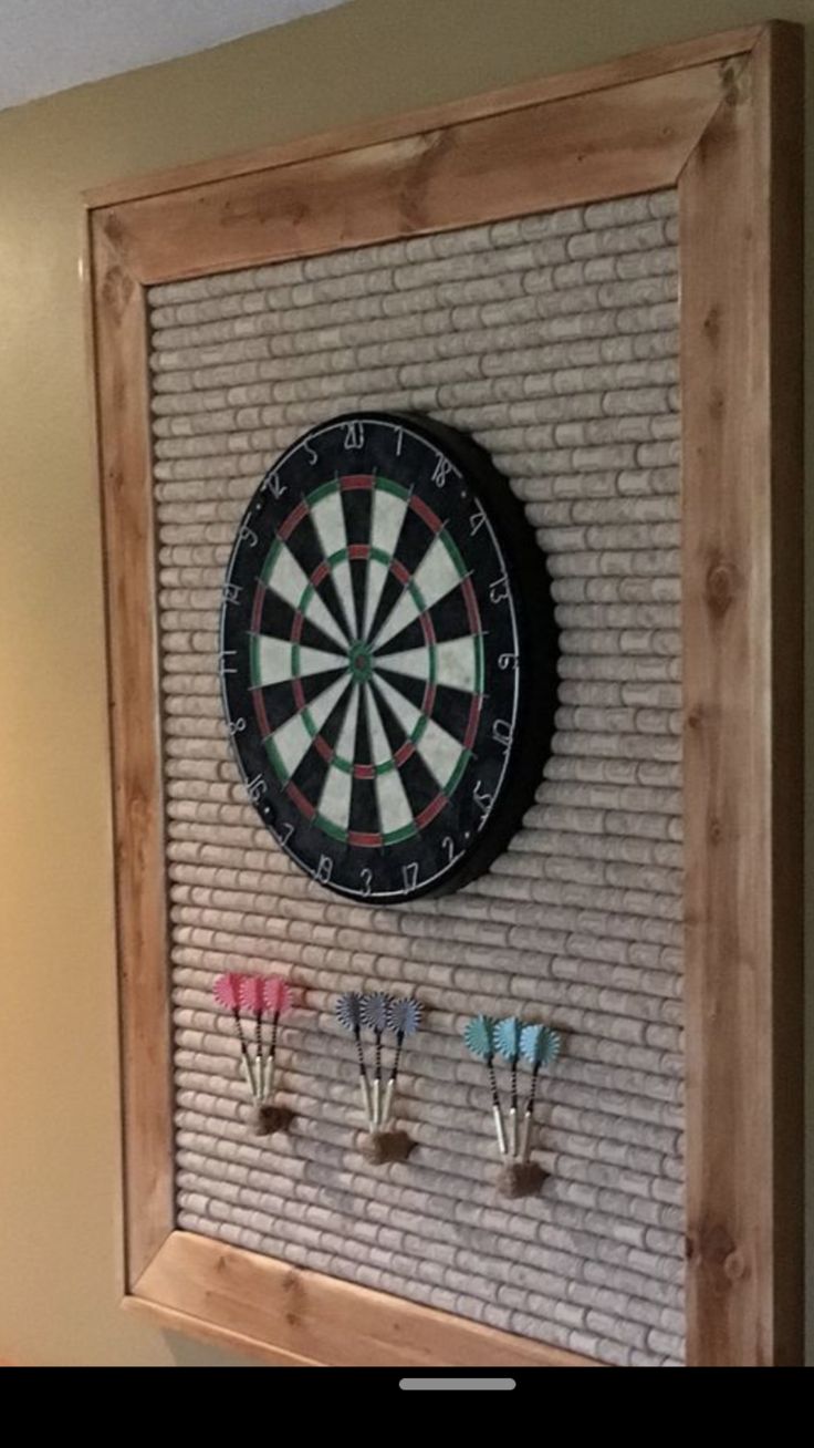 a dart board mounted to the side of a brick wall with three darts on it