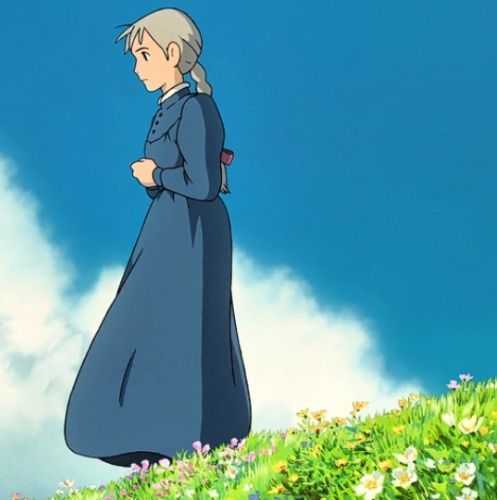 a woman standing on top of a lush green field under a blue cloud filled sky