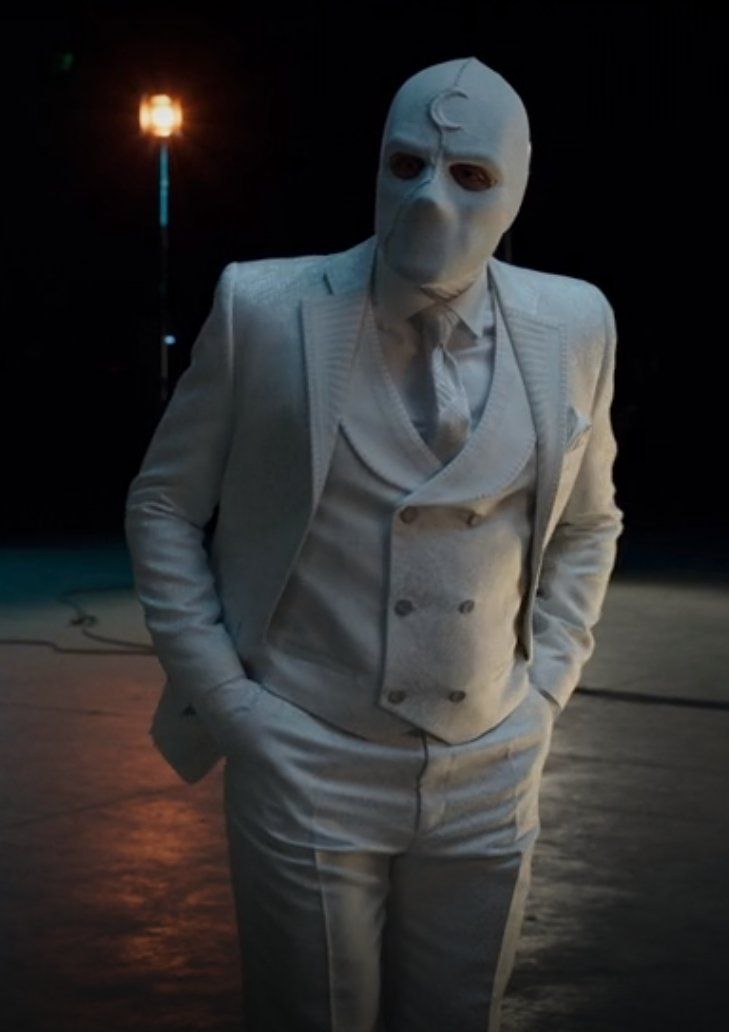 a man in a white suit and mask standing next to a street light