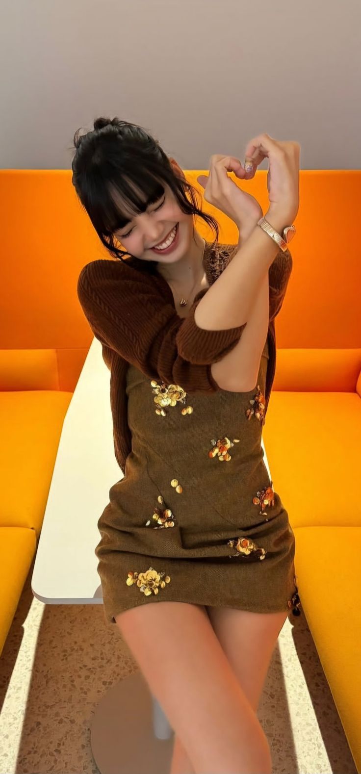 a woman sitting on top of a white table next to an orange couch in a living room