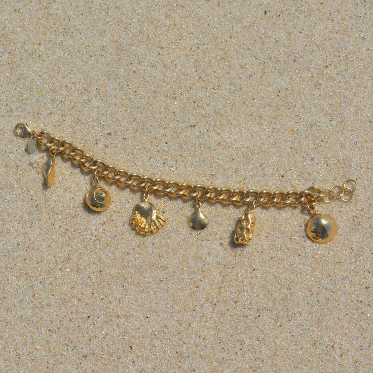 Created with an array of seashells, this is the ultimate beachcombers bracelet. Take a piece of the ocean with you wherever you go and be reminded of nature. We love chunky gold jewelry and this one is a favorite. Gold Filled Curb chain + Extender 6 Charms Cheap Dangle Charm Bracelet With Lobster Clasp, Chunky Gold Charm Bracelet, Ocean Charm Bracelet, Adjustable Gold Charm Bracelet Ocean-inspired, Gold Shell Strand Bracelets, Gold Charm Bracelet With Starfish For Beach, Gold Charm Bracelet With Lobster Clasp For Beach, Beachy Shell Bracelet Jewelry, Beach Charms Bracelet Jewelry