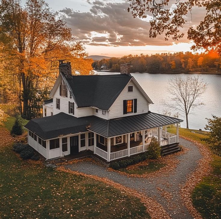 a large white house sitting on top of a lush green field next to a lake