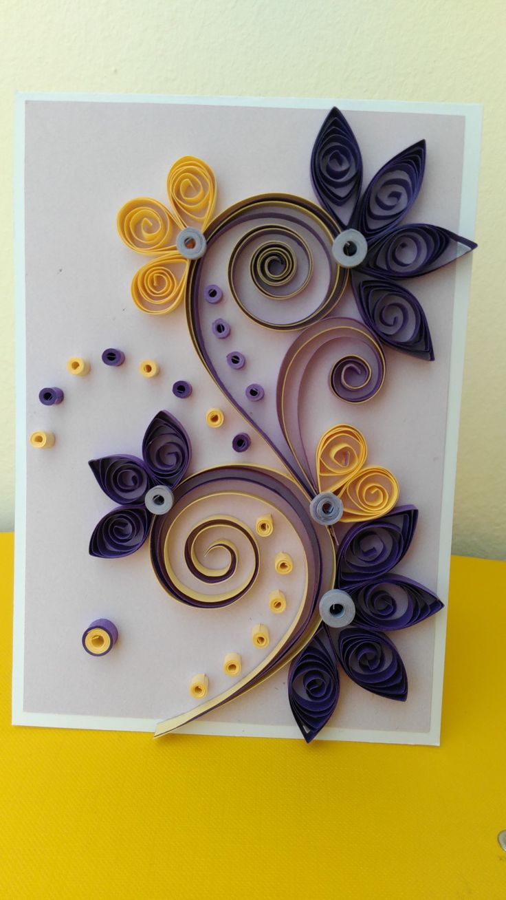 an intricate card with purple, yellow and blue paper flowers on it's side