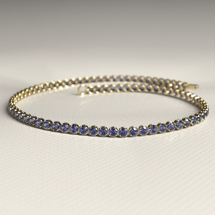 Our Tanzanite Tennis Bracelet, available in 14K or 18K gold, exudes elegance with mesmerizing December birthstone tanzanite, perfect for dainty stacking. This stunning bracelet adds a touch of personal luxury to any look, making it an ideal choice for an anniversary gift or a unique piece of personalized jewelry for her.  𝐅𝐞𝐚𝐭𝐮𝐫𝐞𝐬: * 𝐌𝐚𝐝𝐞 𝐭𝐨 𝐎𝐫𝐝𝐞𝐫 * 𝐌𝐞𝐭𝐚𝐥: 𝟏𝟒𝐊 | 𝟏𝟖𝐊 * 𝐁𝐚𝐧𝐝 𝐂𝐨𝐥𝐨𝐫𝐬: Rose Gold, Yellow Gold & White Gold * 𝐀𝐩𝐩𝐫𝐨𝐱𝐢𝐦𝐚𝐭𝐞 𝐆𝐫𝐨𝐬𝐬 𝐖𝐞 Fine Jewelry Sapphire Bangle Bracelet, 14k Gold Bracelet With 17 Jewels, Flexible Gold Bracelet In Fine Jewelry Style, Fine Jewelry Tanzanite Bracelets For Gift, Fine Jewelry Bracelets With Round Cut Gemstone, Fine Jewelry Gold Flexible Bracelet For Anniversary, 14k Gold Jubilee Bracelet With Round Cut, Round Cut Gemstone Bracelets For Anniversary, Gold Flexible Bracelet For Anniversary, Fine Jewelry