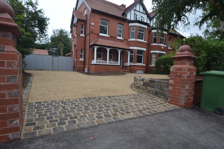 a large red brick house sitting next to a green trash can