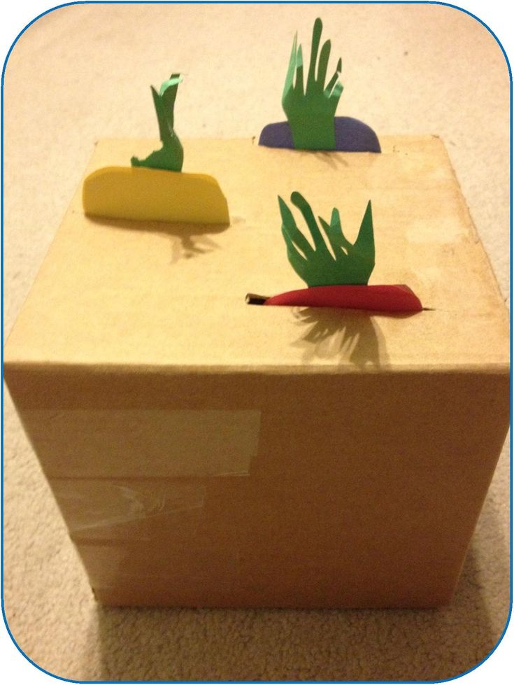 three handprinted objects are placed on top of a cardboard box that is sitting on the floor