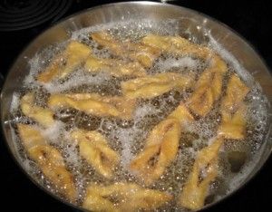 some food is cooking in a pan on the stove top with water and oil around it