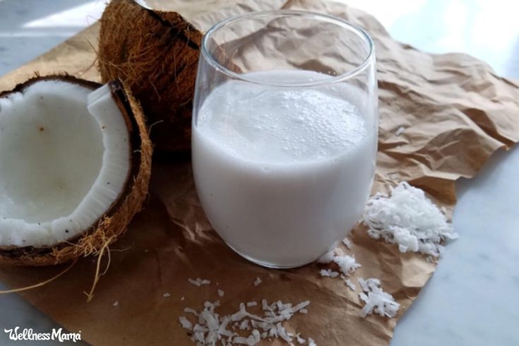 a glass of milk next to a half eaten coconut