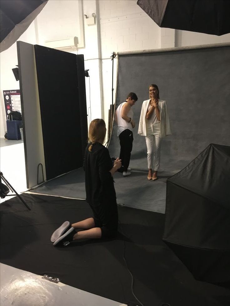 two people are sitting on the ground in front of a camera and another person is standing behind them