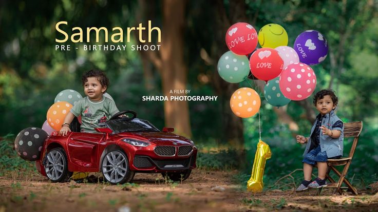 two young boys sitting in a red toy car with balloons on the ground next to them