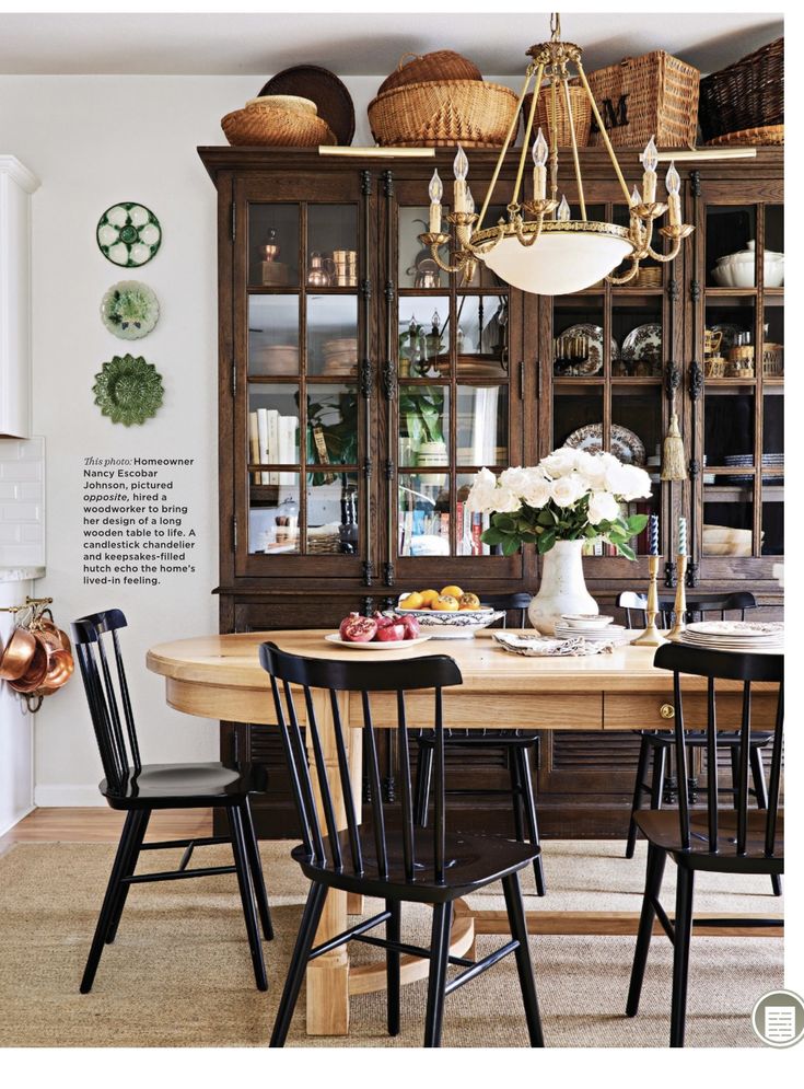 the dining room table is surrounded by black chairs and wicker baskets hanging from the ceiling