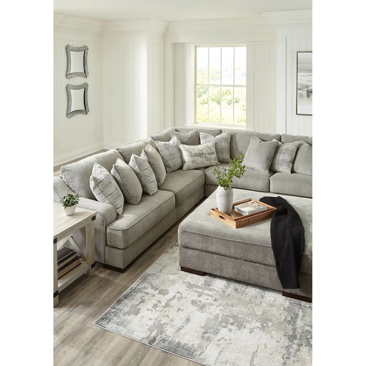 a living room with a large sectional couch and coffee table in the corner, along with a rug on the floor