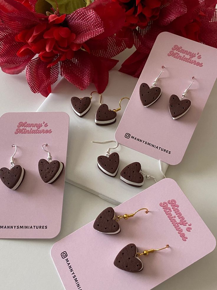 three pairs of heart shaped earrings sitting on top of each other next to a red flower