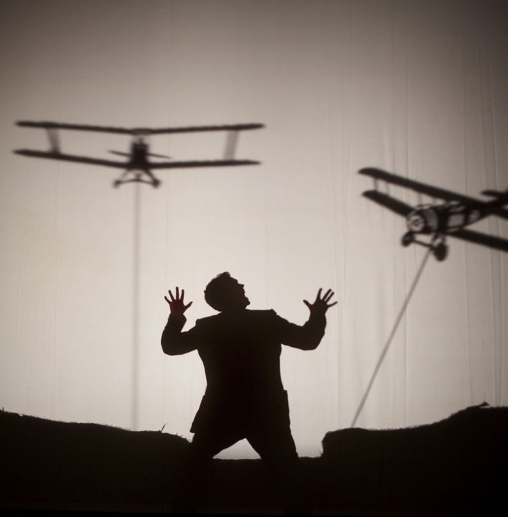 the silhouette of a man standing in front of two remote controlled planes flying above him