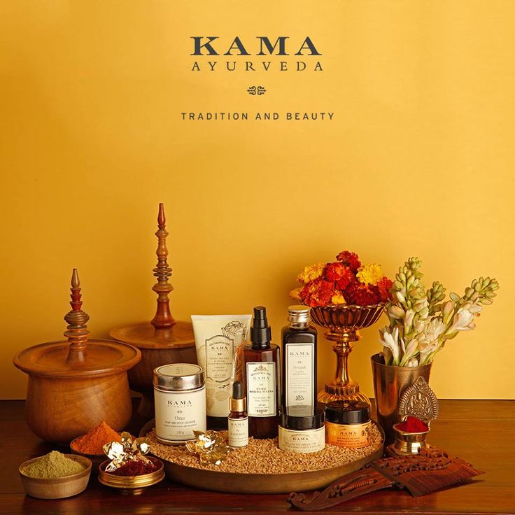 a wooden table topped with bottles and containers filled with flowers next to a yellow wall