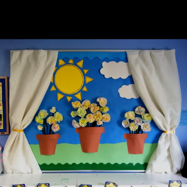 a table with flowers on it in front of a blue wall and white drapes