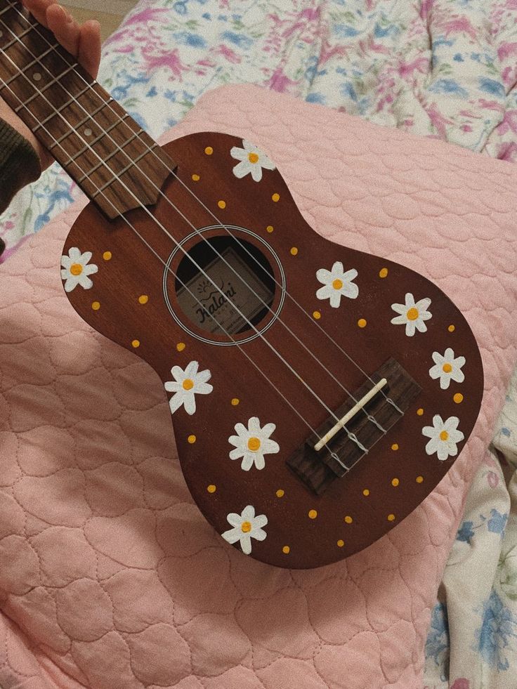 a ukulele with flowers painted on it sitting on a bed