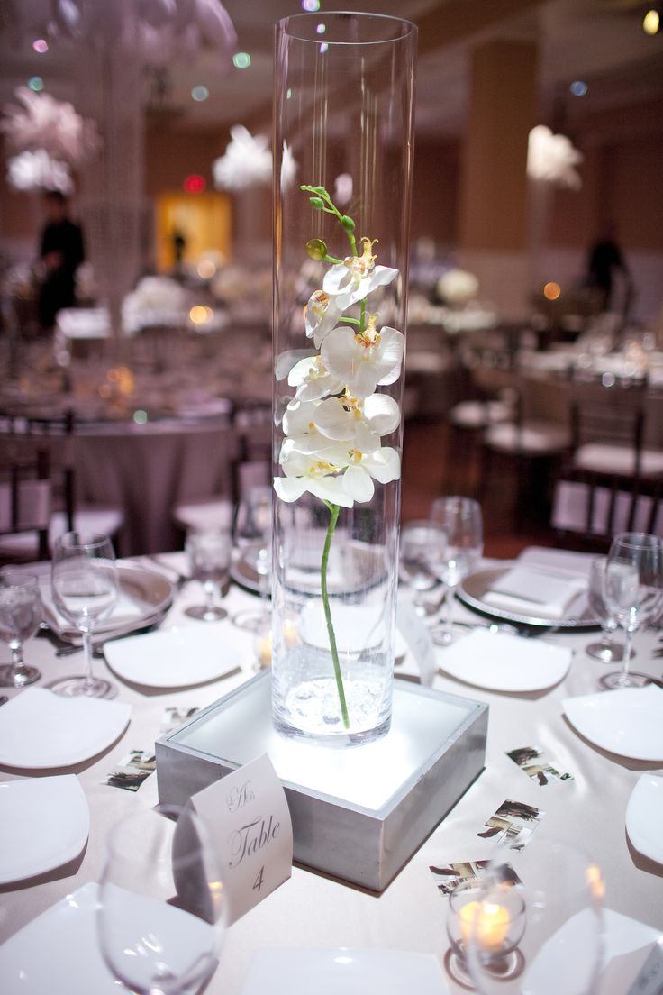 there is a vase with flowers in it on top of a table set for an event