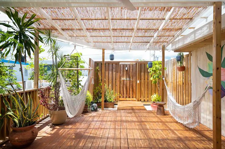 a wooden deck with hammock and potted plants