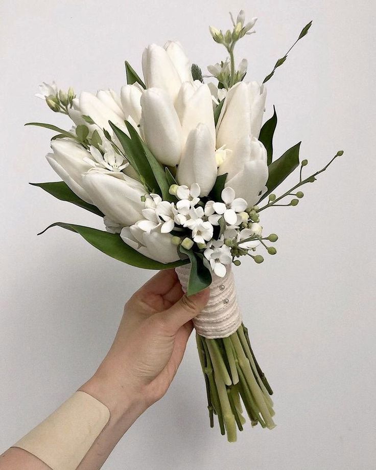 a hand holding a bouquet of white flowers