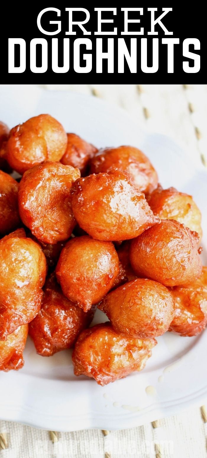 a white plate topped with fried doughnuts covered in powdered sugar and sitting on a table