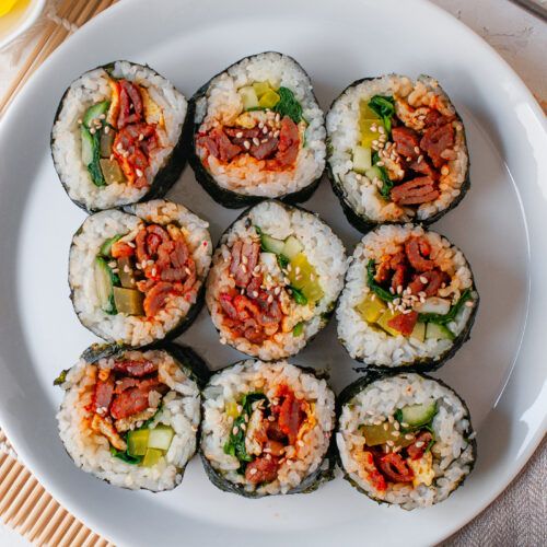 sushi rolls are arranged on a white plate next to a glass of orange juice