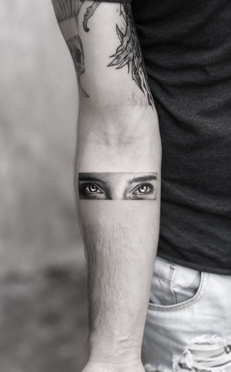 a man's arm with an eye tattoo on the left side of his arm