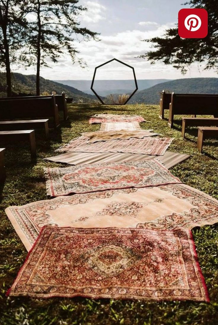 rows of rugs lined up on the ground in front of some benches and trees