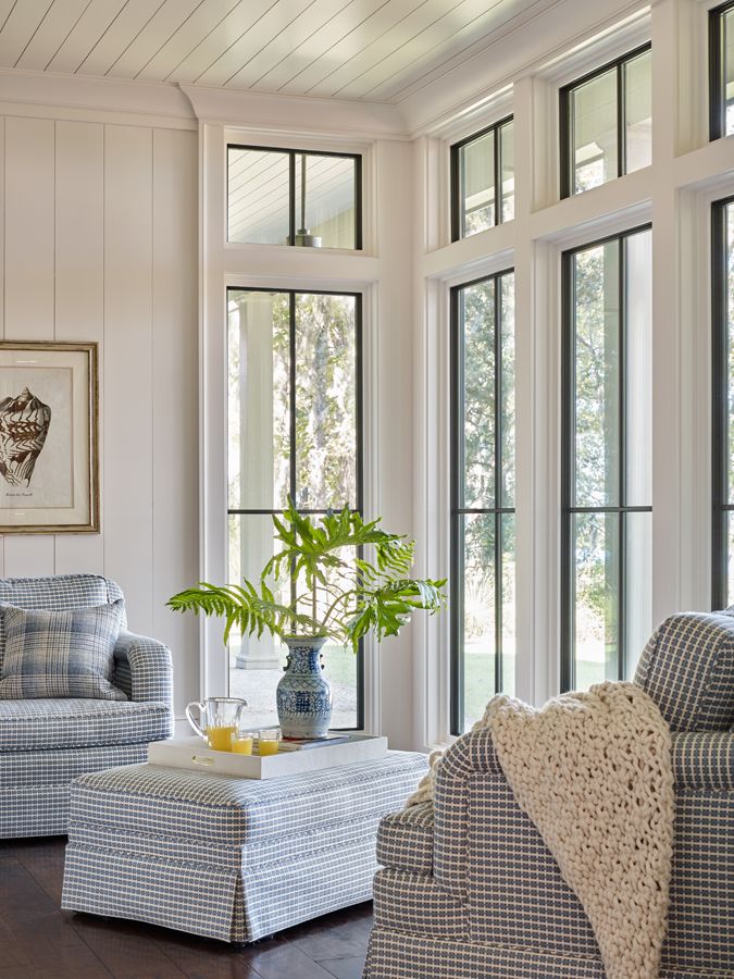 a living room filled with furniture and windows next to a wooden floor covered in wood planks