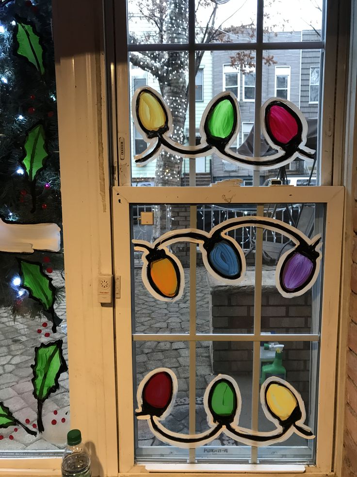 a stained glass window with christmas decorations on the windowsill and tree in the background