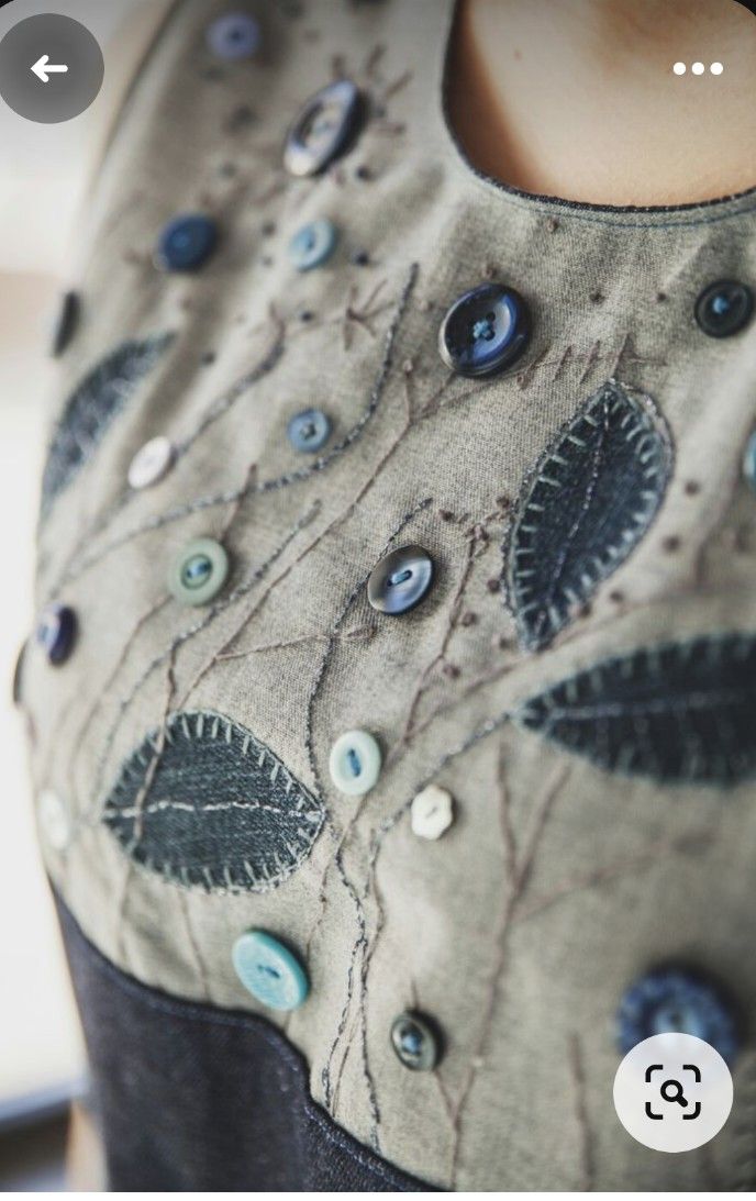 a close up of a dress with buttons and flowers on the front, as well as an applique