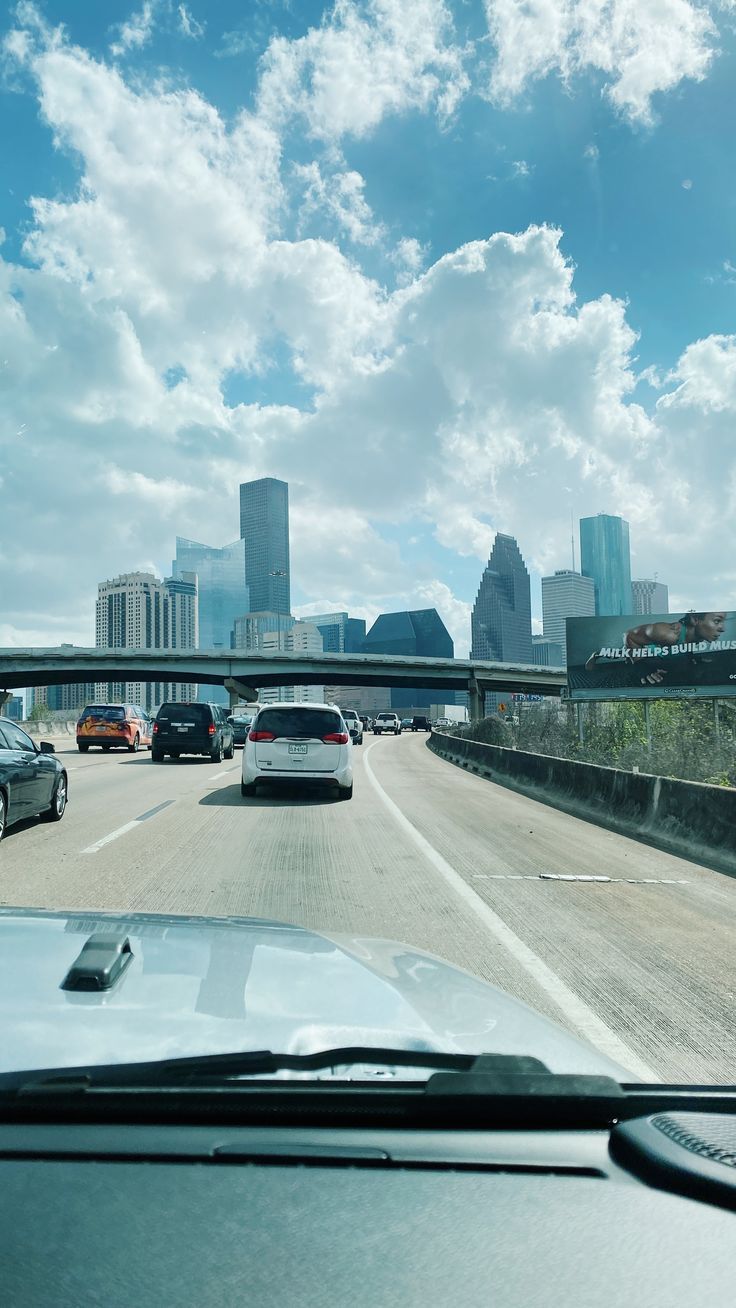 cars driving down the highway in front of tall buildings