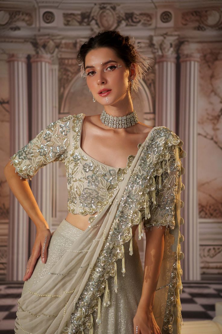 Step into glamour with this exquisite gray sari, crafted from luxurious sequined fabric. The heavy skirt provides a stunning foundation, while the draped pallu is fully embroidered, featuring beautiful long tassels that add a playful touch. The padded blouse ensures a flattering fit, making this ensemble perfect for grand occasions where elegance and sophistication are essential. Embrace the allure of this captivating outfit, designed to make a lasting impression. Sequence Fabric, Skirt Saree, Sequence Skirt, Sari Skirt, Sequined Fabric, Sequined Skirt, Beaded Work, Tuxedo Accessories, Grey Saree