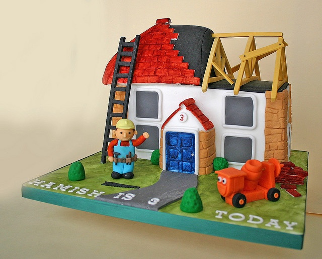 a birthday cake with a fireman next to a house and ladder on top of it