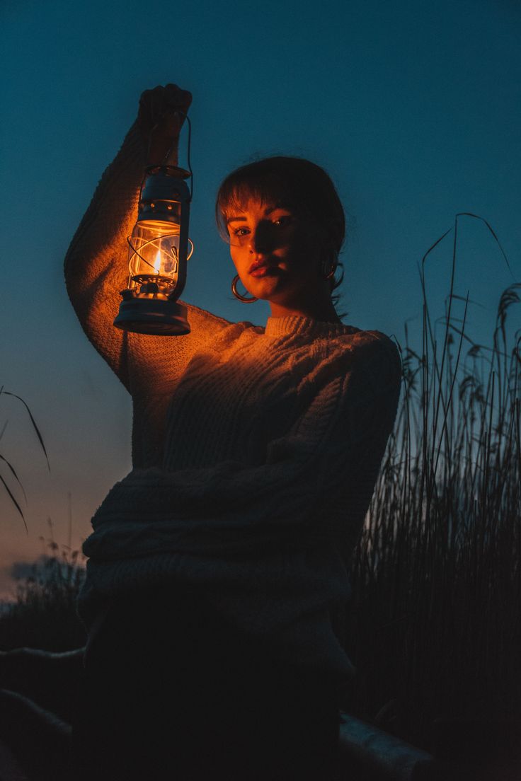 a woman holding a lantern in the dark