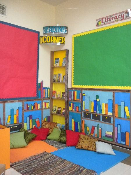 a room with colorful bookshelves and pillows on the floor in front of it