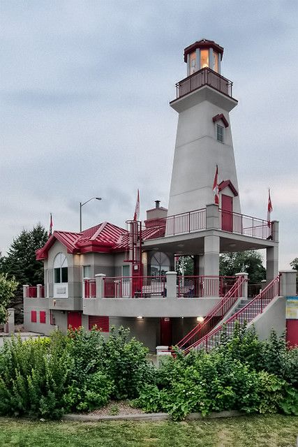 a lighthouse with red and white paint on it's side next to some bushes