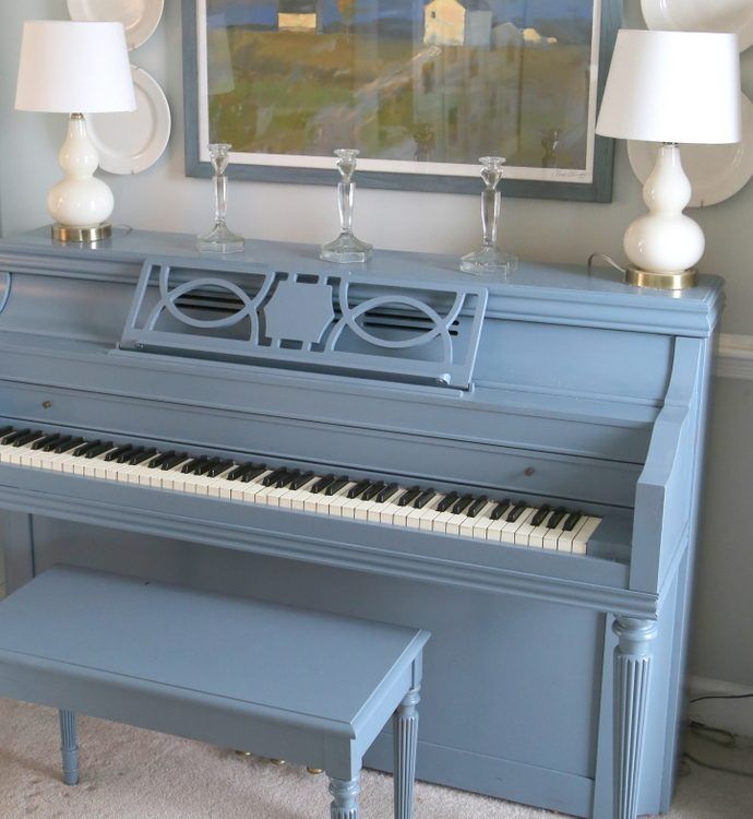 a blue piano in a living room next to two lamps and a painting on the wall