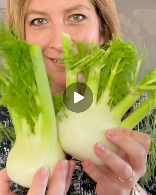 a woman holding up some green vegetables in her hands