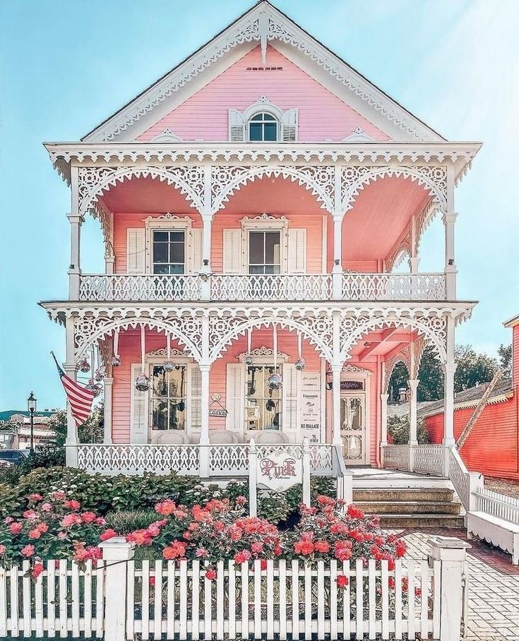 a pink house with white picket fence and flowers